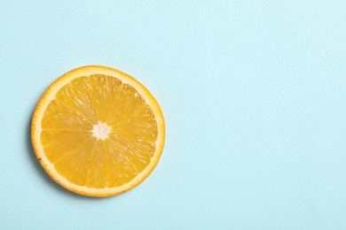 Slice of juicy orange on light blue background, top view. Space for text