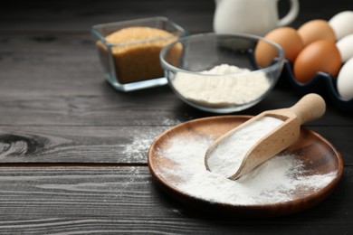 Baking powder and other products on black wooden table, closeup. Space for text