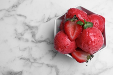 Photo of Yummy strawberry ice cream in bowl on white marble table, top view. Space for text