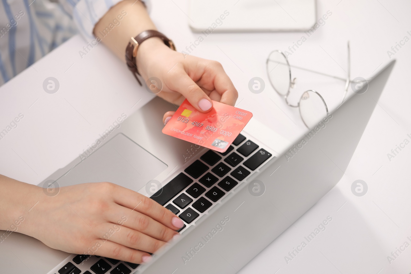 Photo of Woman with credit card using laptop for online shopping at white table, closeup