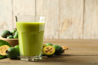 Fresh feijoa smoothie and fresh fruits on wooden table, closeup. Space for text