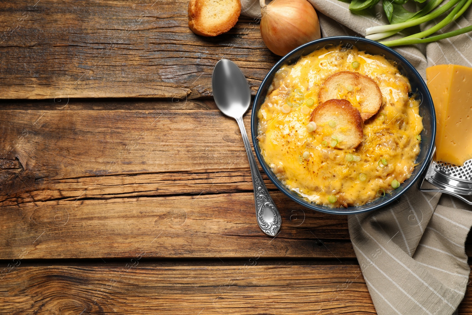 Photo of Tasty homemade French onion soup on wooden table, flat lay. Space for text