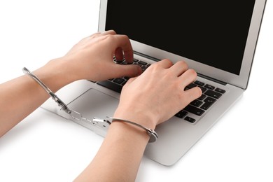 Photo of Woman in handcuffs typing on laptop against white background, closeup. Internet addiction