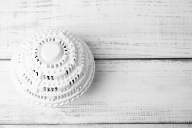 Photo of Laundry dryer ball on white wooden table, top view. Space for text