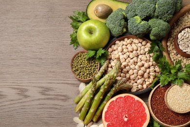 Fresh vegetables, fruits and seeds on wooden table, flat lay. Space for text