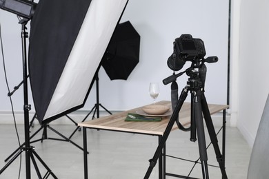 Photo of Table with stylish dinnerware in front of camera and professional lighting equipment indoors. Photo studio set