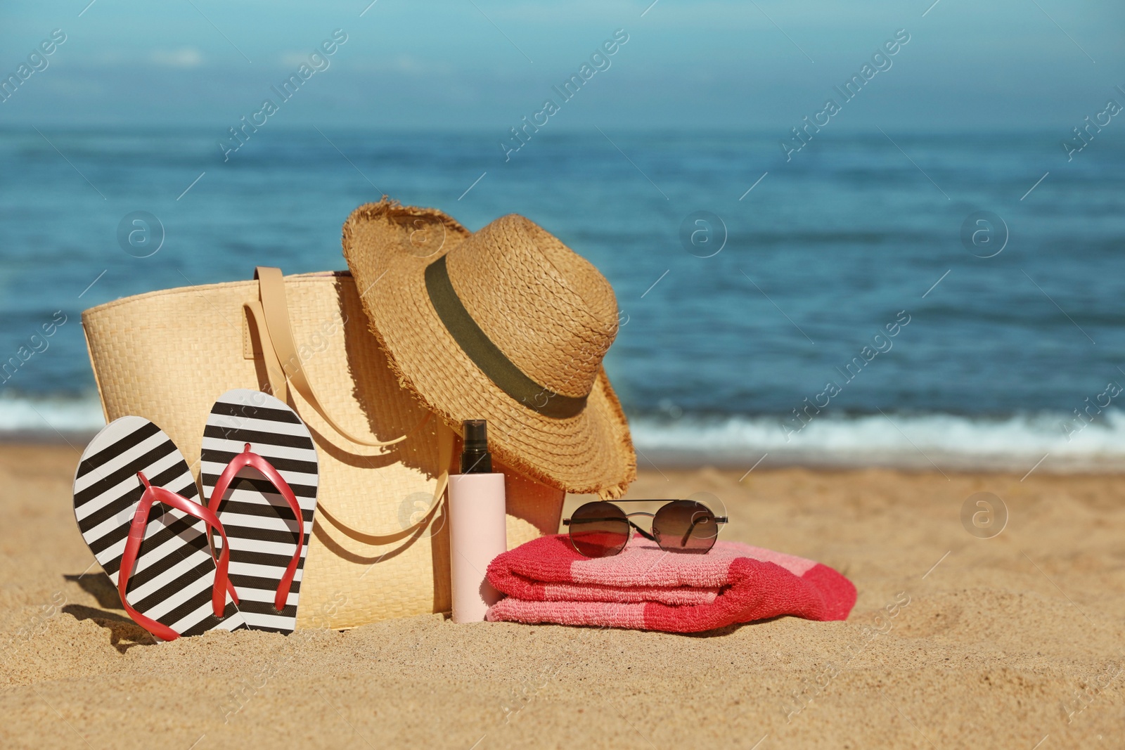 Photo of Straw hat, bag and other beach items on sandy seashore, space for text