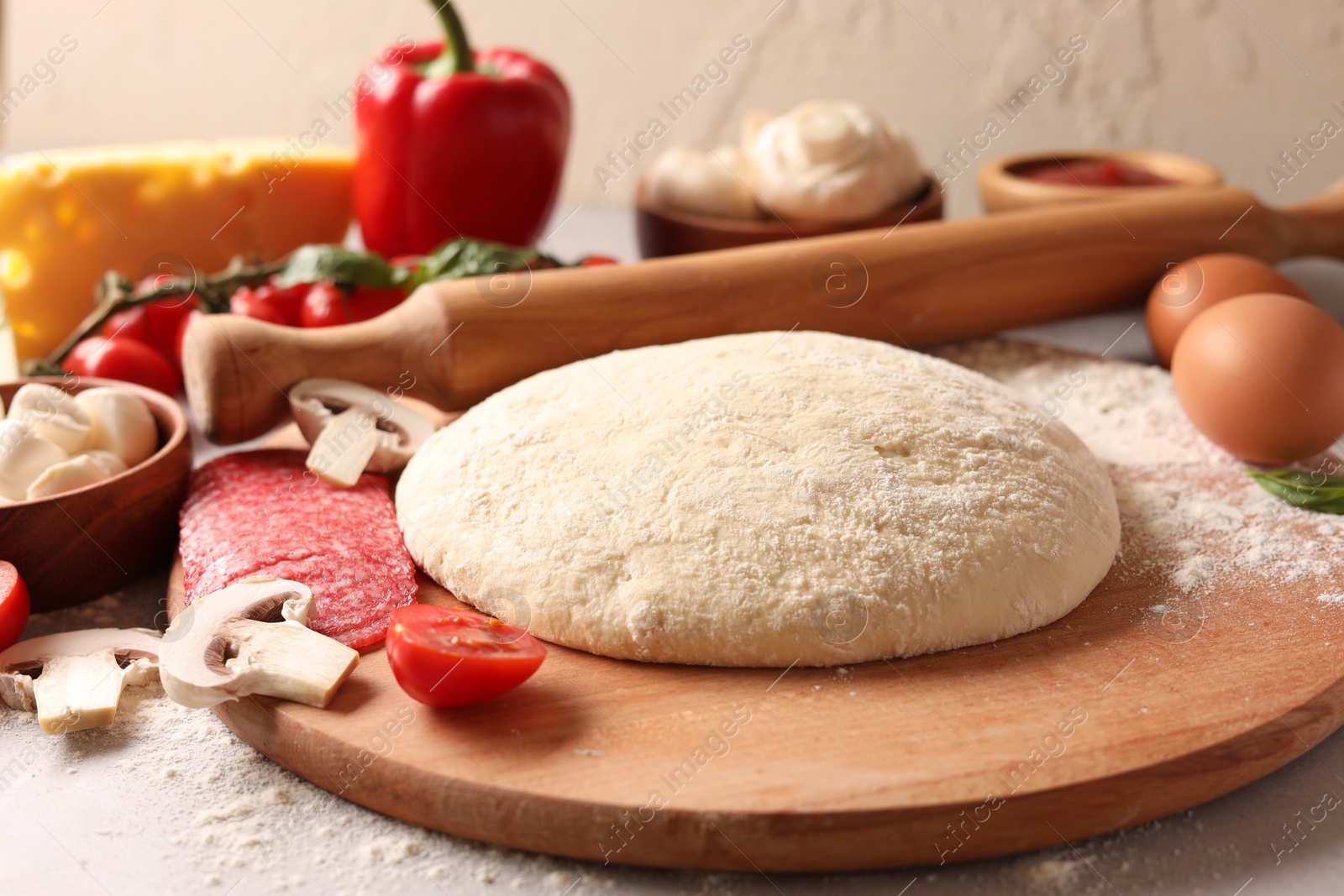 Photo of Pizza dough, products and rolling pin on gray table, closeup