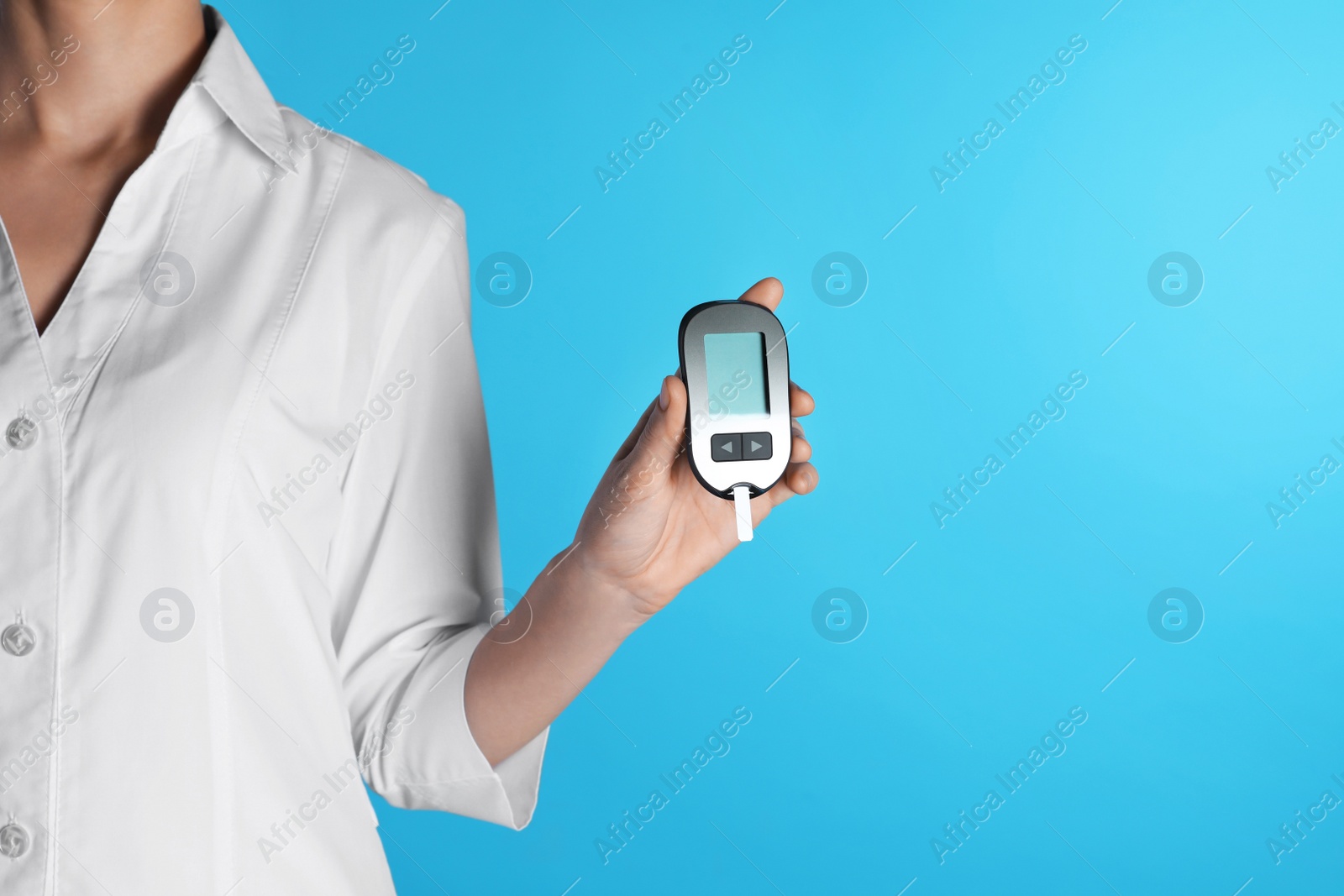 Photo of Female doctor holding digital glucometer on color background, closeup view with space for text. Medical object