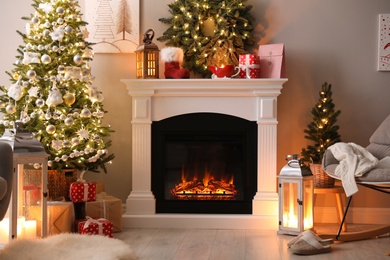 Photo of Beautiful fireplace, Christmas tree and other decorations in living room. Interior design