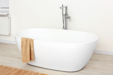 Photo of Beautiful white tub with towel in bathroom. Interior design