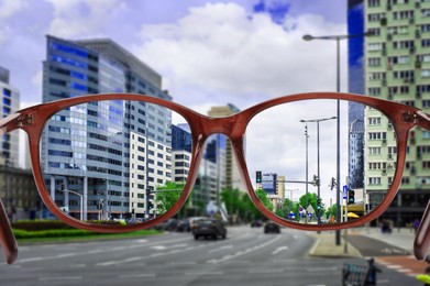 Image of Vision correction. Cityscape becoming clearer when looking through glasses