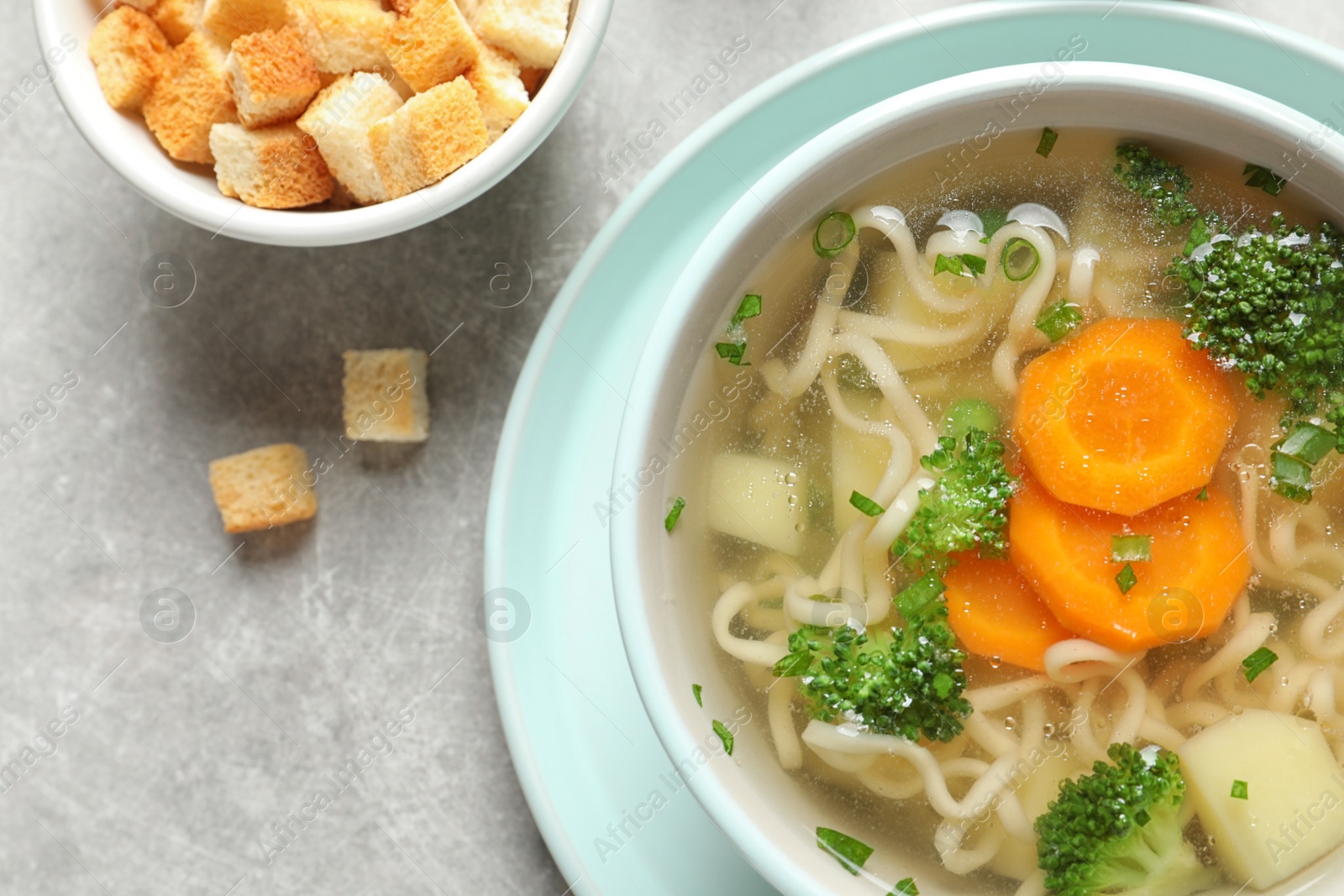 Photo of Bowl of fresh homemade vegetable soup served on light grey table, flat lay. Space for text