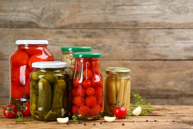 Photo of Jars of pickled vegetables on wooden table