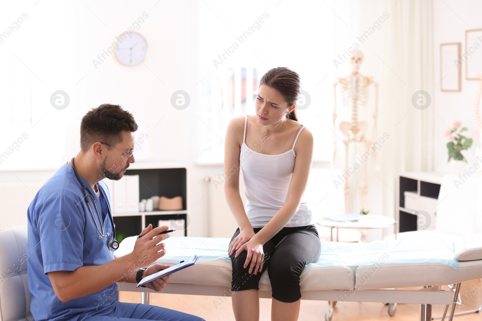 Photo of Male orthopedist examining patient with injured leg in clinic