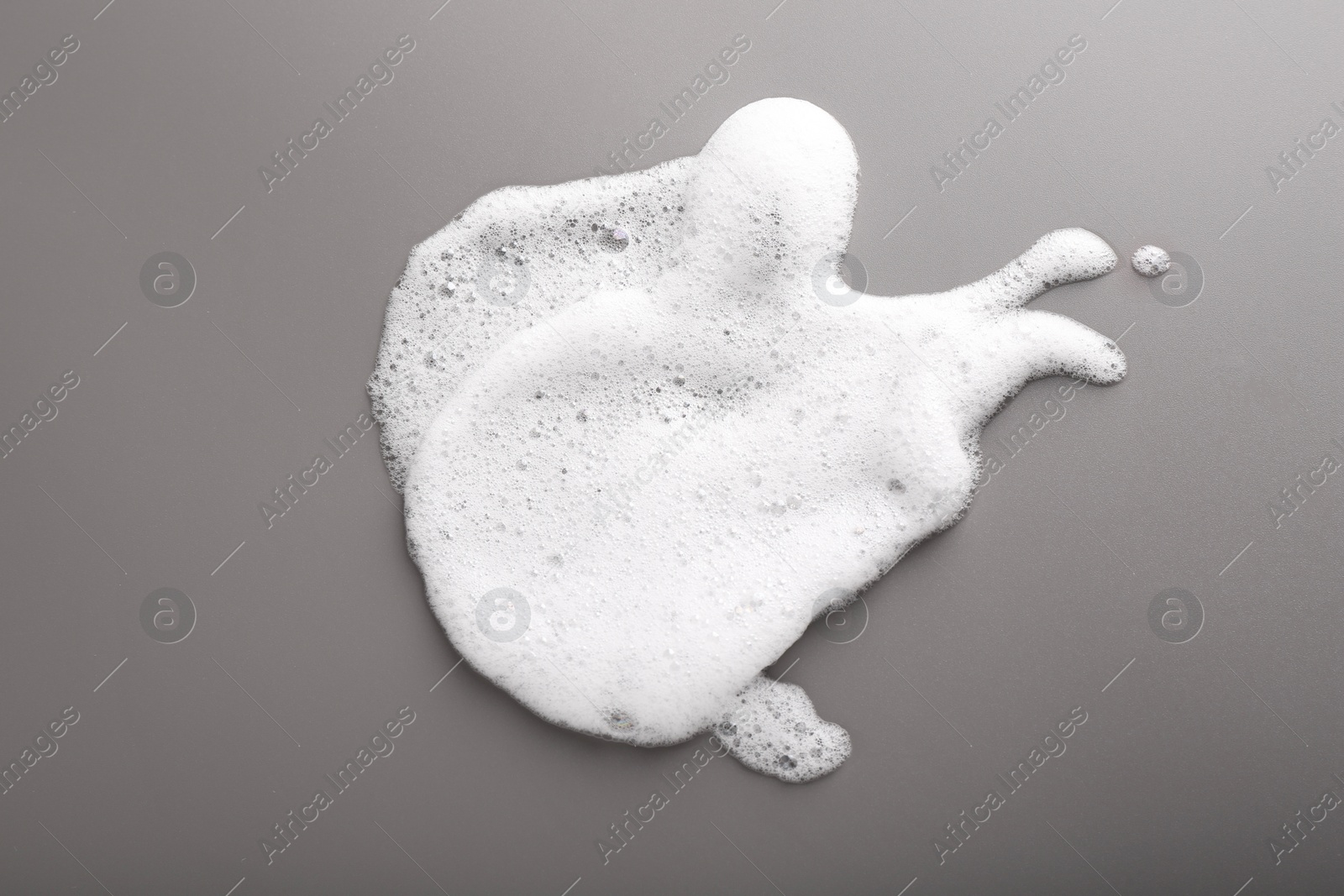 Photo of White foam with bubbles on grey background, top view