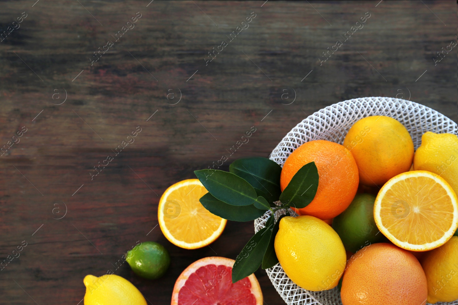 Photo of Different citrus fruits and leaves on wooden table, flat lay. Space for text