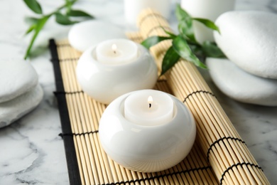 Photo of Beautiful spa composition with candles and bamboo mat on marble background