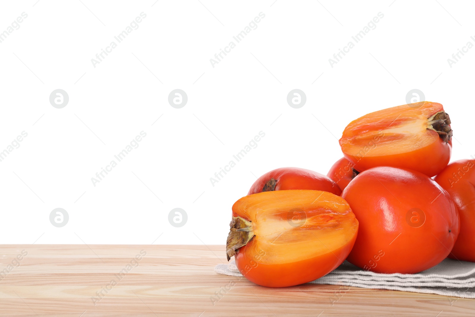 Photo of Delicious ripe juicy persimmons and napkin on wooden table against white background