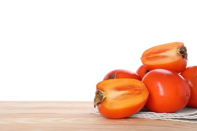 Photo of Delicious ripe juicy persimmons and napkin on wooden table against white background