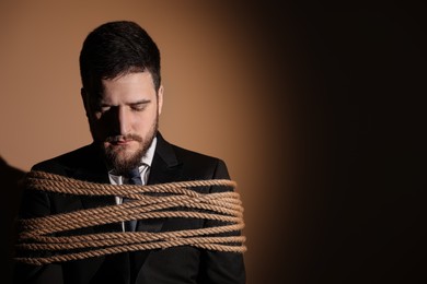 Photo of Man tied up and taken hostage on dark background. Space for text