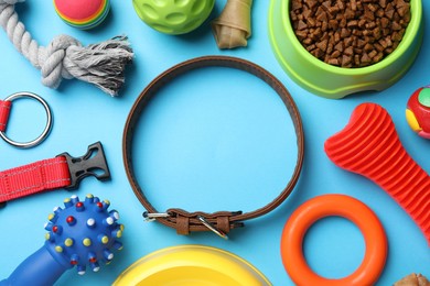Flat lay composition with dog collar, toys and food on light blue background