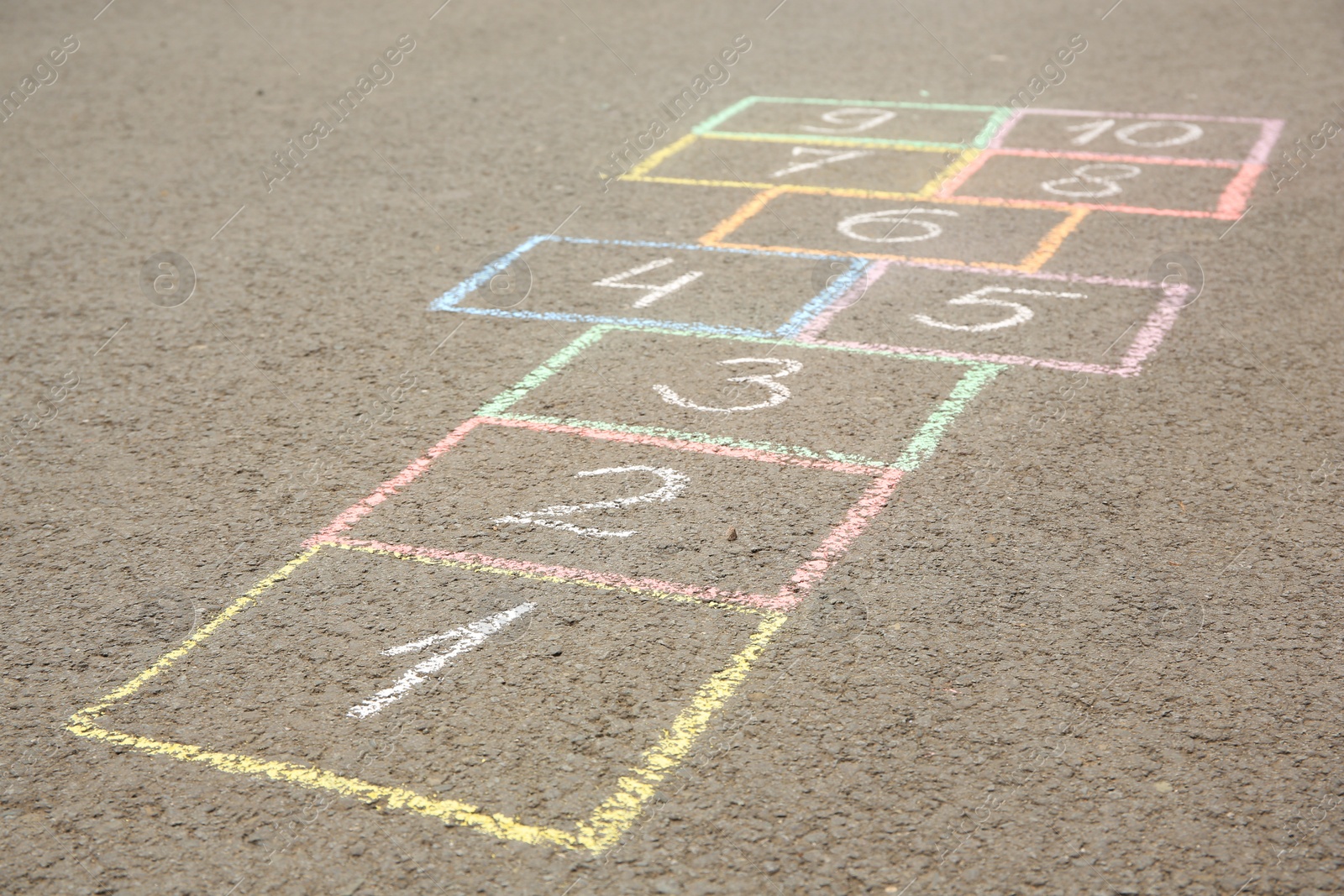 Photo of Hopscotch drawn with colorful chalk on asphalt outdoors, closeup