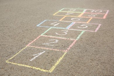 Hopscotch drawn with colorful chalk on asphalt outdoors, closeup