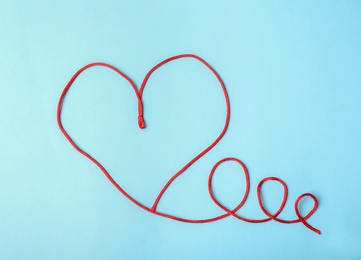 Photo of Heart made of red string on light background, top view