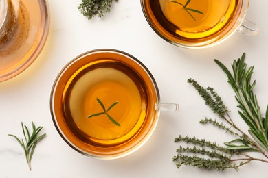 Photo of Aromatic herbal tea with thyme and rosemary on white marble table, flat lay