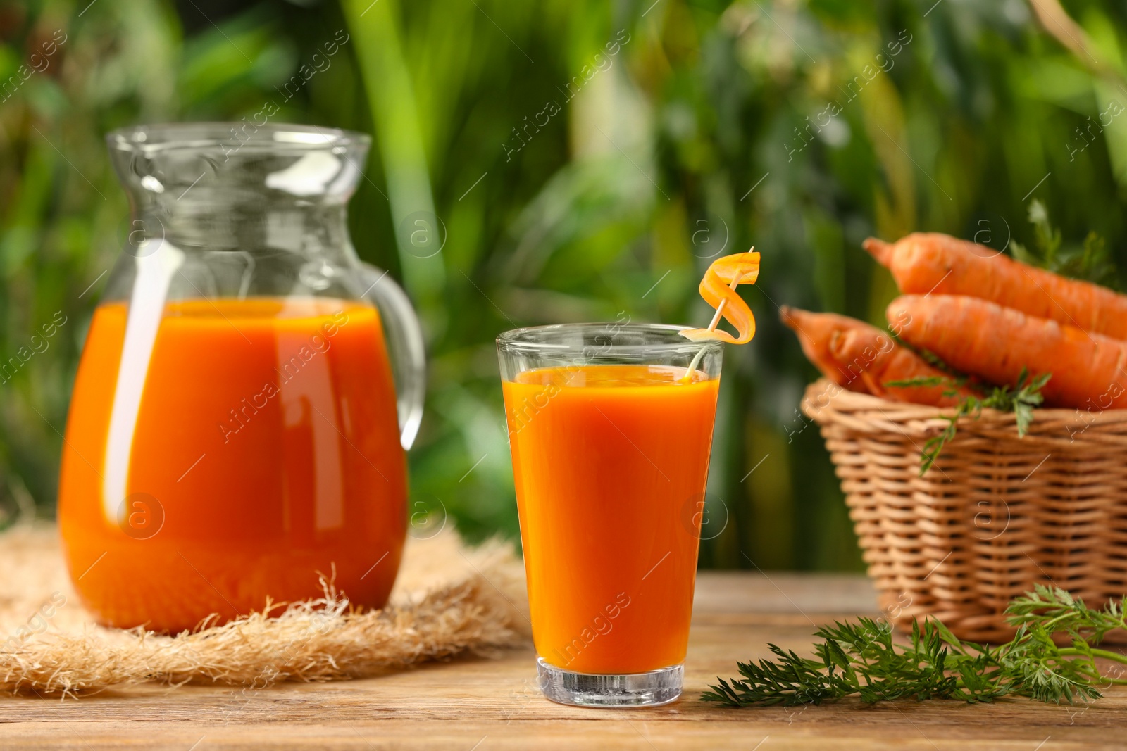 Photo of Tasty juice and carrot on wooden table outdoors