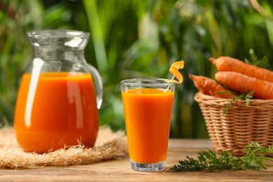 Photo of Tasty juice and carrot on wooden table outdoors