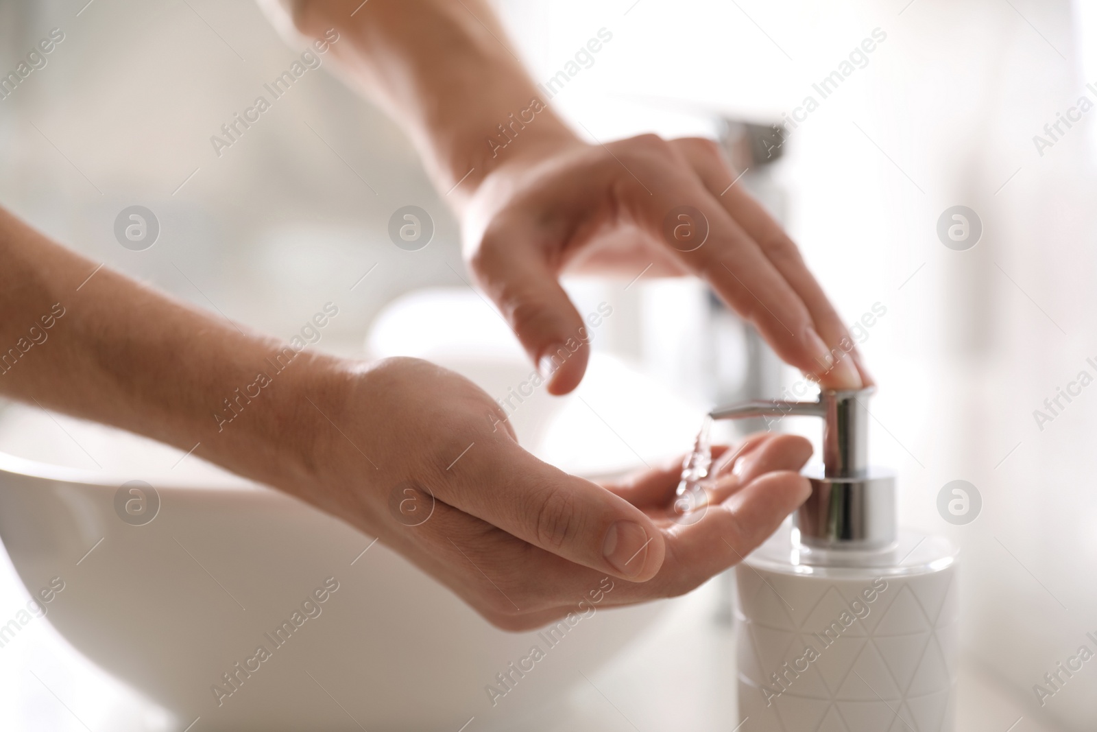 Photo of Man using soap dispenser in bathroom, closeup