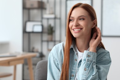 Portrait of beautiful smiling young woman. Happy lady with red hair at home. Space for text