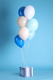 Photo of One gift box and balloons on light blue background