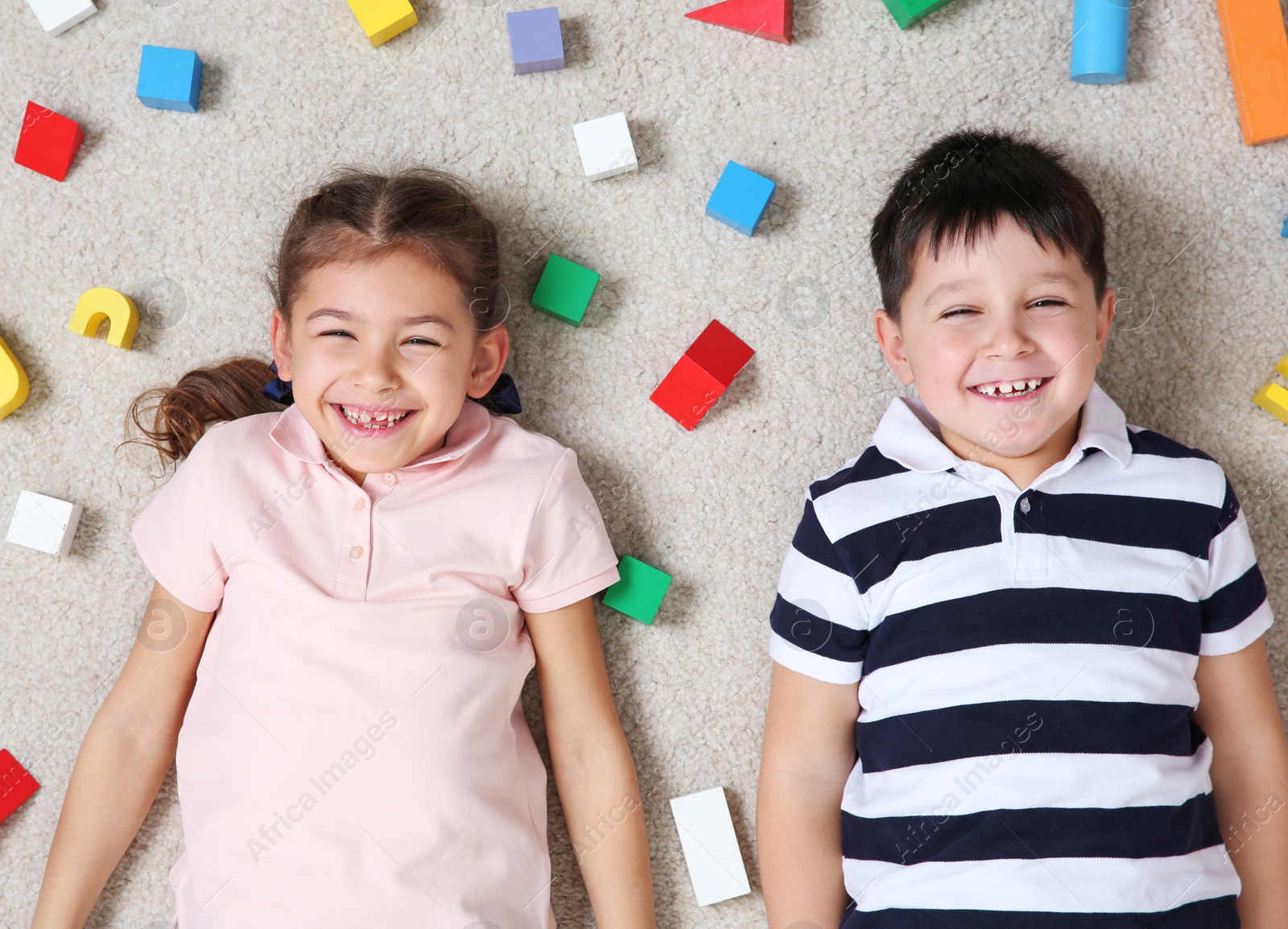 Photo of Cute children playing with colorful blocks on floor indoors, top view