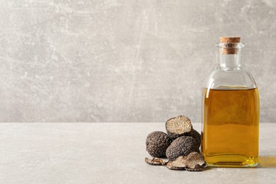 Photo of Fresh truffles and oil on light grey table, space for text