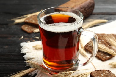 Photo of Mug of delicious kvass, spikes and bread on table