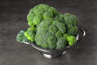 Colander with fresh raw broccoli on grey table