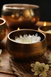 Tibetan singing bowls and beautiful chrysanthemum flowers on wooden table, closeup