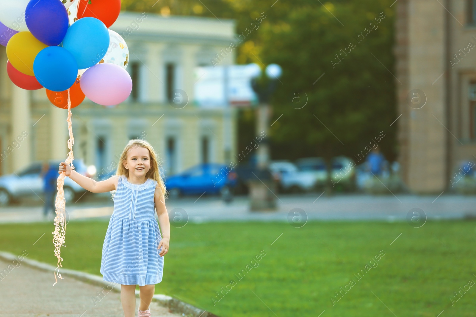 Photo of Little girl with colorful balloons outdoors on sunny day