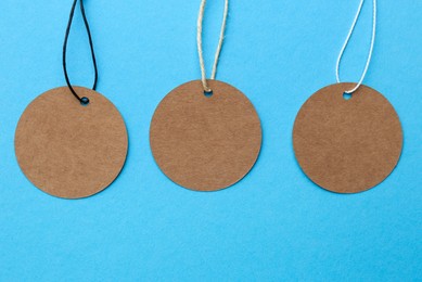 Photo of Circle shaped tags with space for text on light blue background, top view