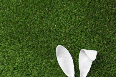 Funny Easter bunny ears on green grass, top view with space for text