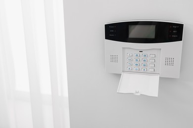 Photo of Home security alarm system on white wall indoors, space for text