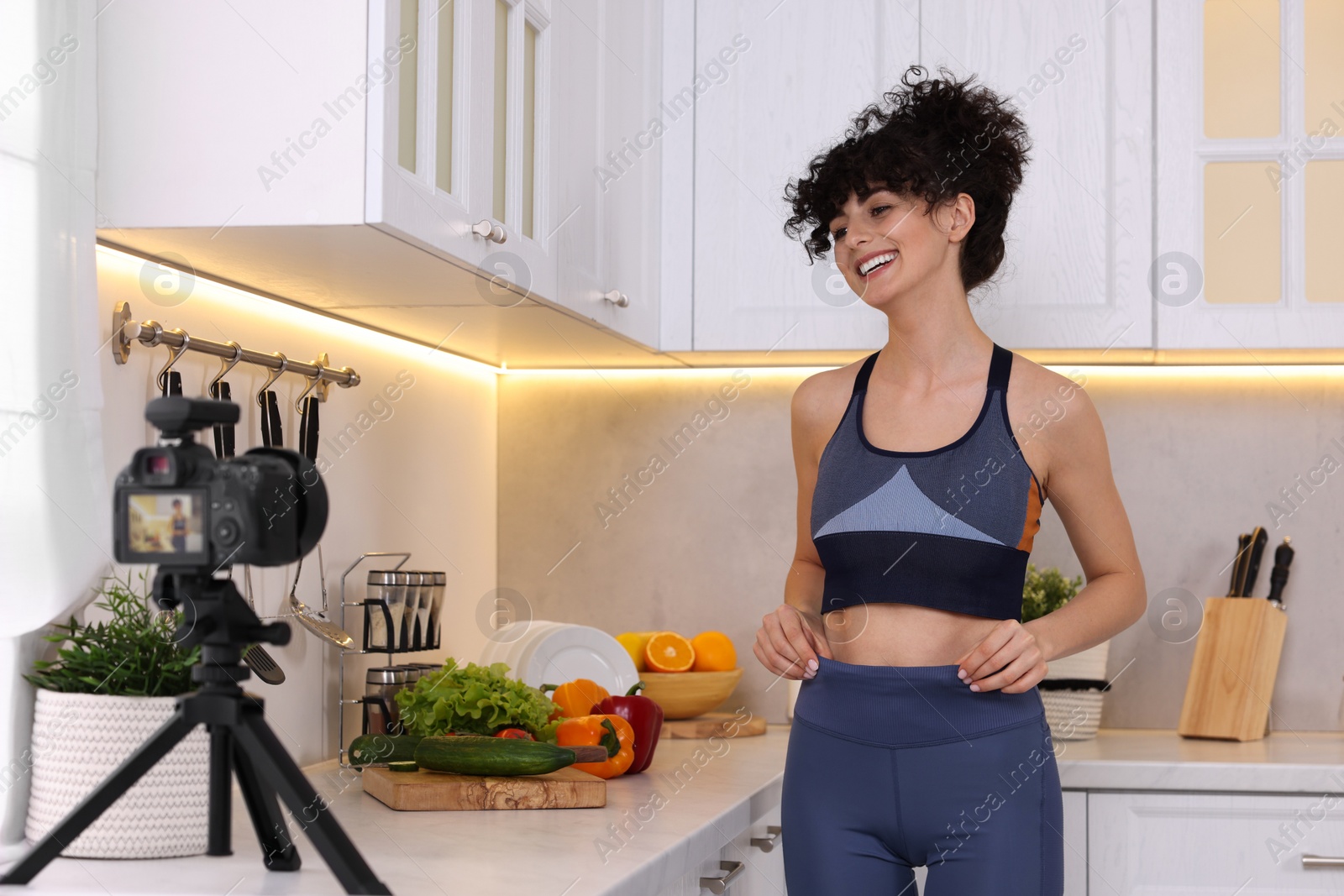 Photo of Smiling food blogger recording video in kitchen