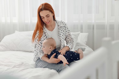 Photo of Mother playing with her cute baby in bedroom