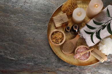 Spa composition. Brushes, bottles and sea salt on grey textured table, top view. Space for text