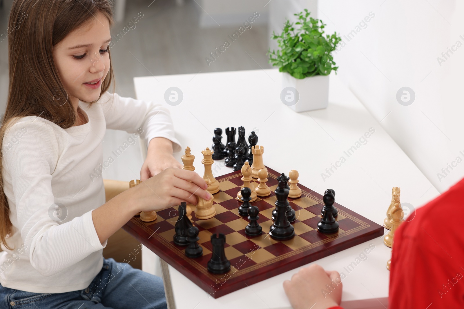 Photo of Cute children playing chess at table in room