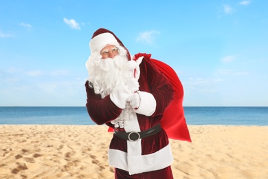 Image of Santa Claus with sack on beach near sea. Christmas vacation
