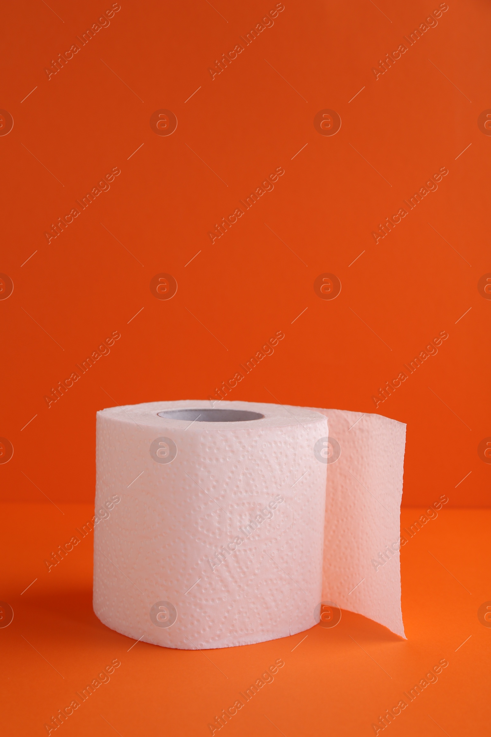 Photo of Soft toilet paper roll on orange background. Space for text